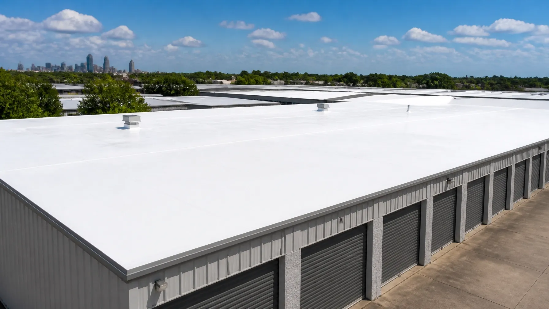 Finished white reflective coating across a self-storage roof beneath a clear Texas sky
